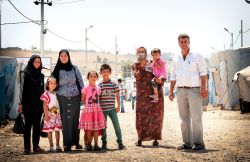 A displaced family in a refugee camp, consisting of a man, three women, and four children.
