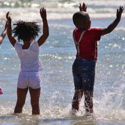 Three children in Africa, playing in the sea, as a symbol of hope for the developing world's future.