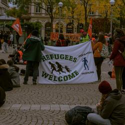 A demonstration in Germany in support of refugees, with signs reading 'refugees welcome' and 'stop racial profiling'. 