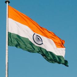 The flag of India, flown at the top of a pole, blowing in the wind.