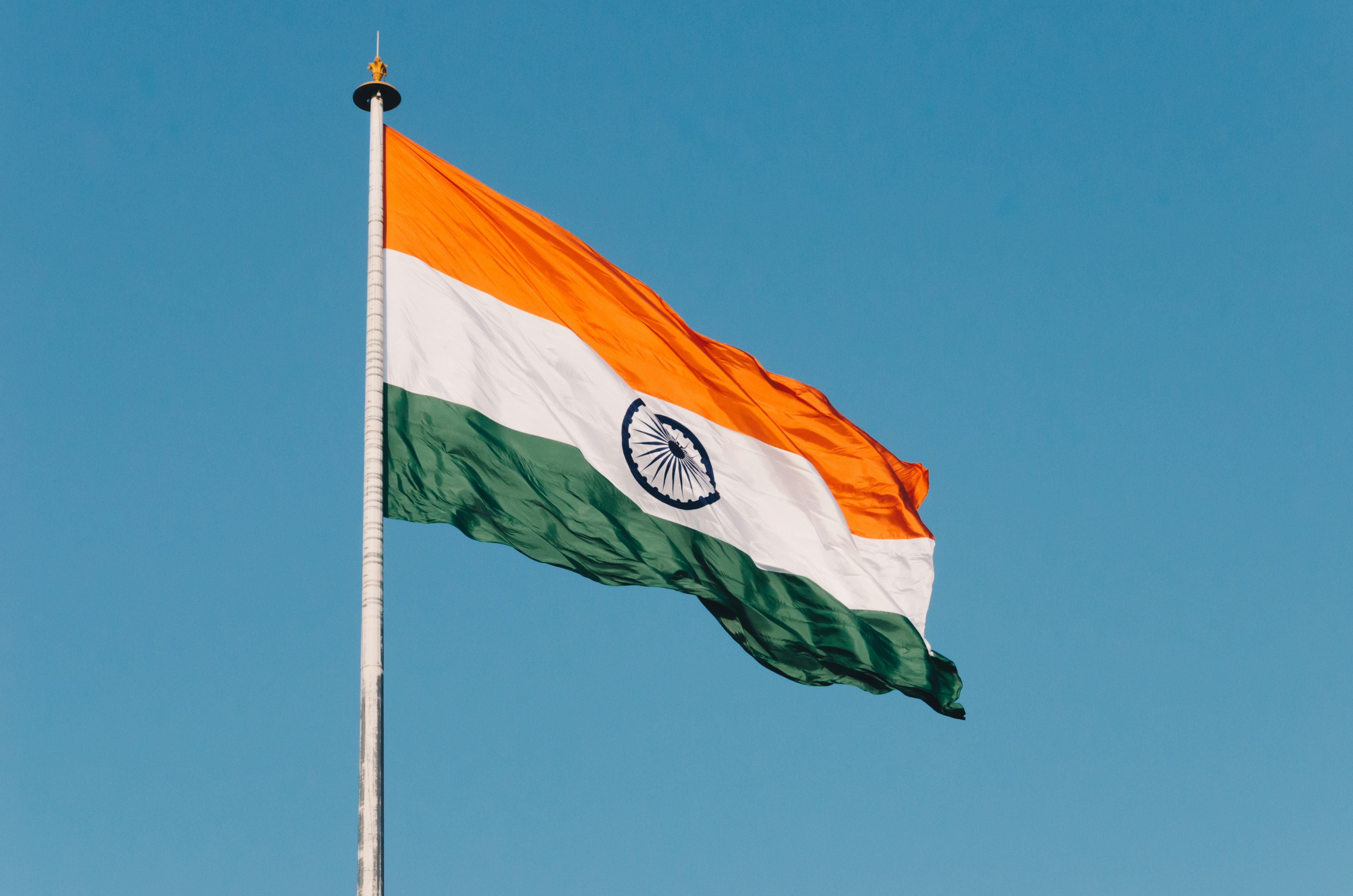 The flag of India. The national flag of India, hoisted at the top of a flagpole, being blown by a strong breeze.