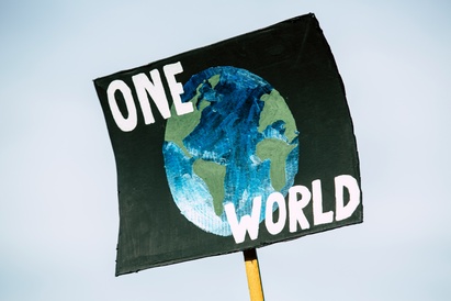 A sign at a climate protest reading 'One World', emphasising the need for international effort to tackle climate change.