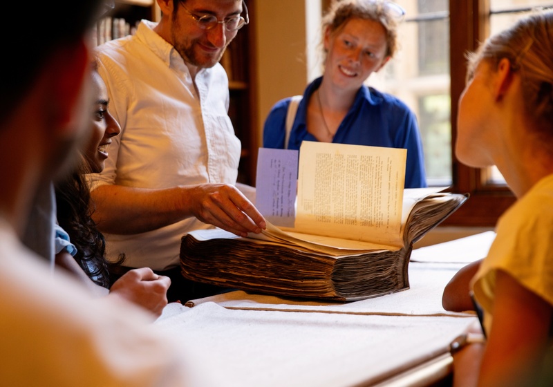 A group of University of Cambridge students looking at books at the Gonville and Caius College library. Copyright: University of Cambridge (June 2023)