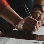 Person with orange long-sleeved shirt write on piece of paper
